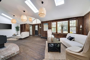 A spacious living room with a fireplace, a sofa, a coffee table, and a TV mounted on the wall.