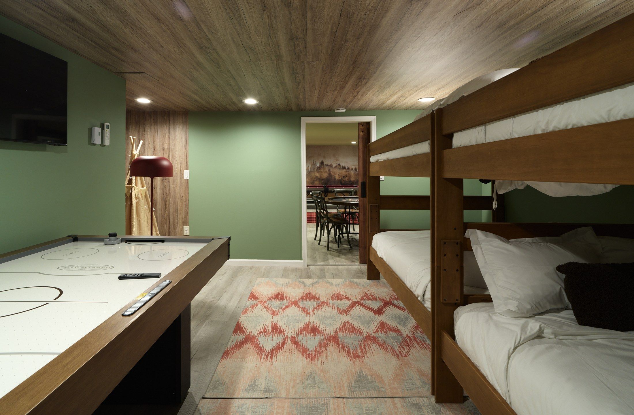 A room with bunk beds, a pool table, and a dining area.