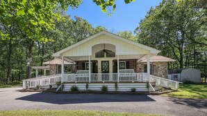 A two-story building with a porch and a covered front entrance. - Premium Restored Cabin | Pocono Mountains (Barrett Township)