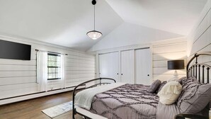 A bedroom with a bed, a nightstand, a lamp, and a window. - Premium Restored Cabin | Pocono Mountains (Barrett Township)