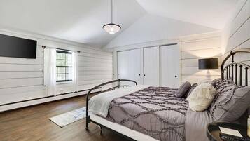 A bedroom with a bed, a nightstand, a lamp, and a window.