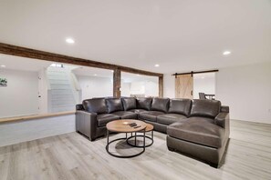 A modern living room with a sectional sofa, a round coffee table, and a staircase leading to an upper level.