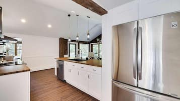A modern kitchen with white cabinetry, a stainless steel refrigerator, and wooden flooring.