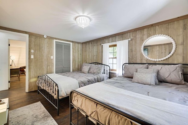 A bedroom with two beds, a mirror, and a chandelier.
