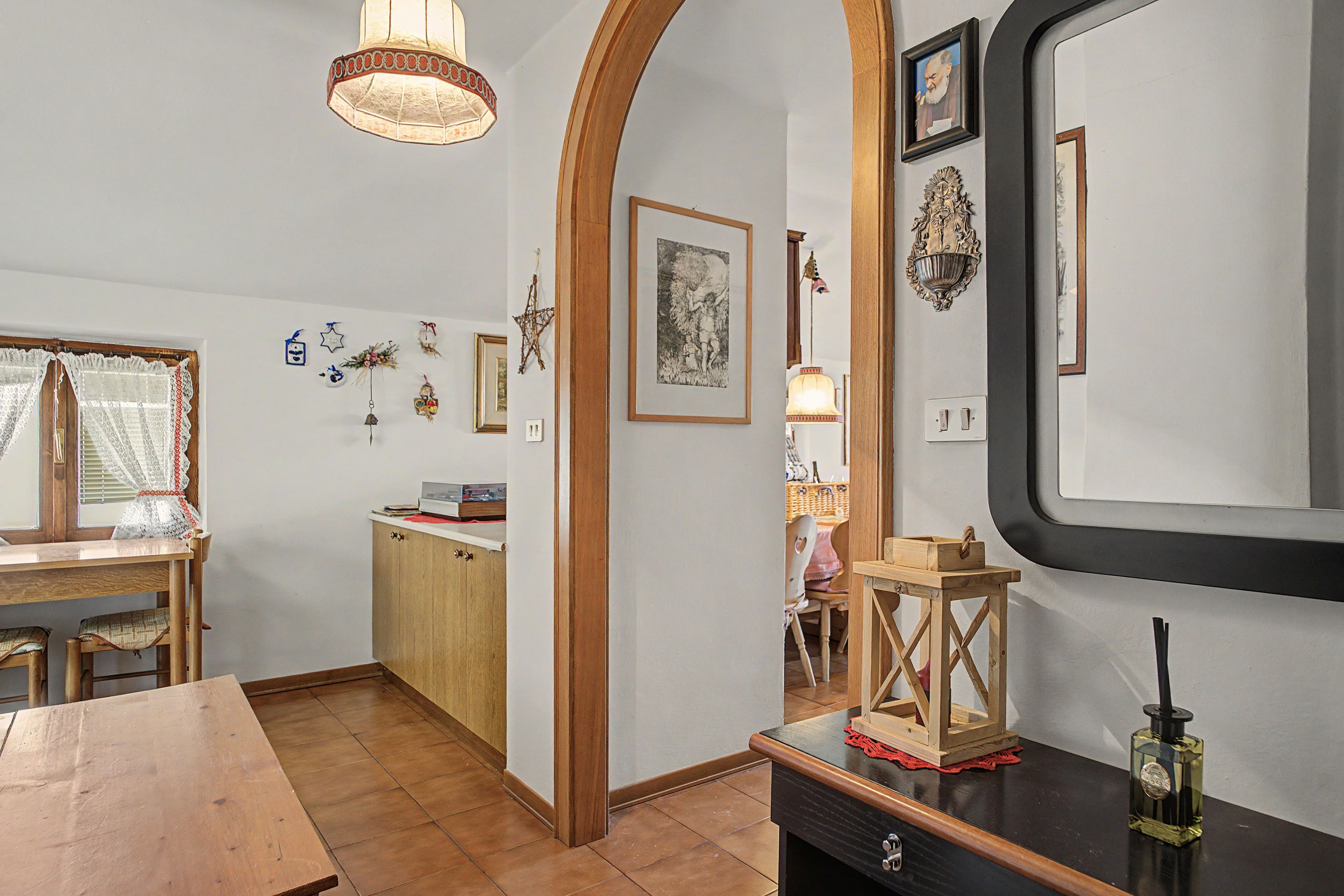 Una habitació amb taula de fusta, cadires, un armari i un mirall a la paret.