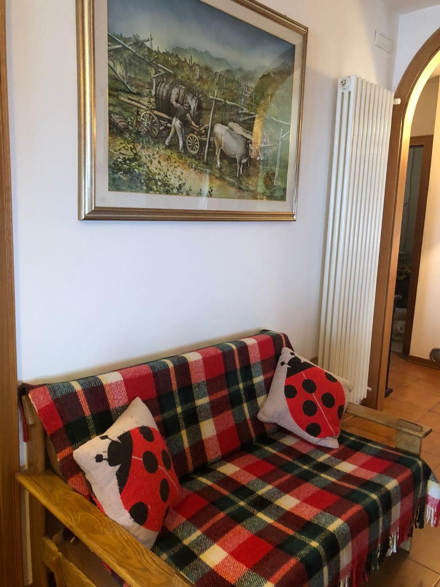 Ein Zimmer mit einer Couch, einem gerahmten Gemälde und einer Heizung.