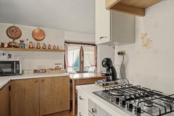 A kitchen with a microwave, coffee maker, and gas stove.