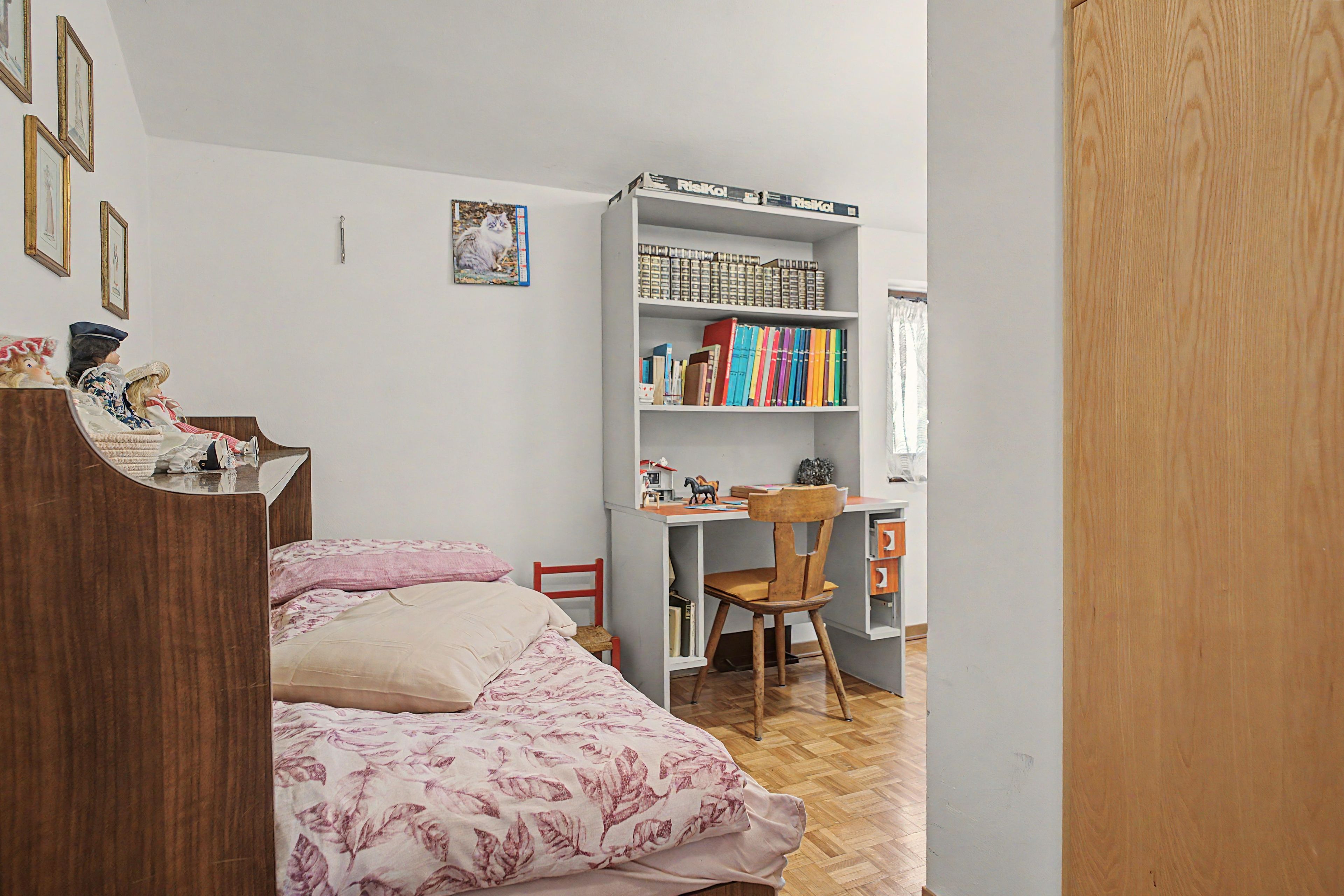 Une chambre à coucher avec un lit, une armoire en bois, une bibliothèque et un bureau.