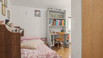 Une chambre à coucher avec un lit, une armoire en bois, une bibliothèque et un bureau.