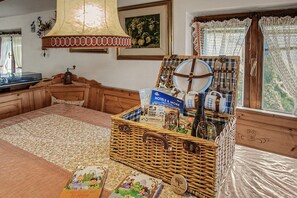 Una habitación acogedora con una cama grande, una cesta de mimbre llena de objetos y una ventana con cortinas.