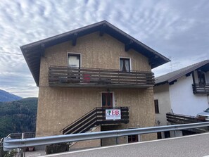 A two-story building with a balcony, a signboard, and a view of the mountains. - 'Il Rifugio del Brunone' Apartment with Mountain View, Balcony and Wi-Fi (Valda)