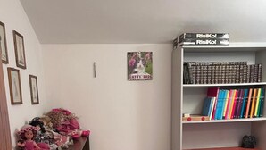 Ein Schlafzimmer mit einem Bett, einem Schreibtisch, einem Stuhl, einem Bücherregal und einer Wand mit gerahmten Bildern.
