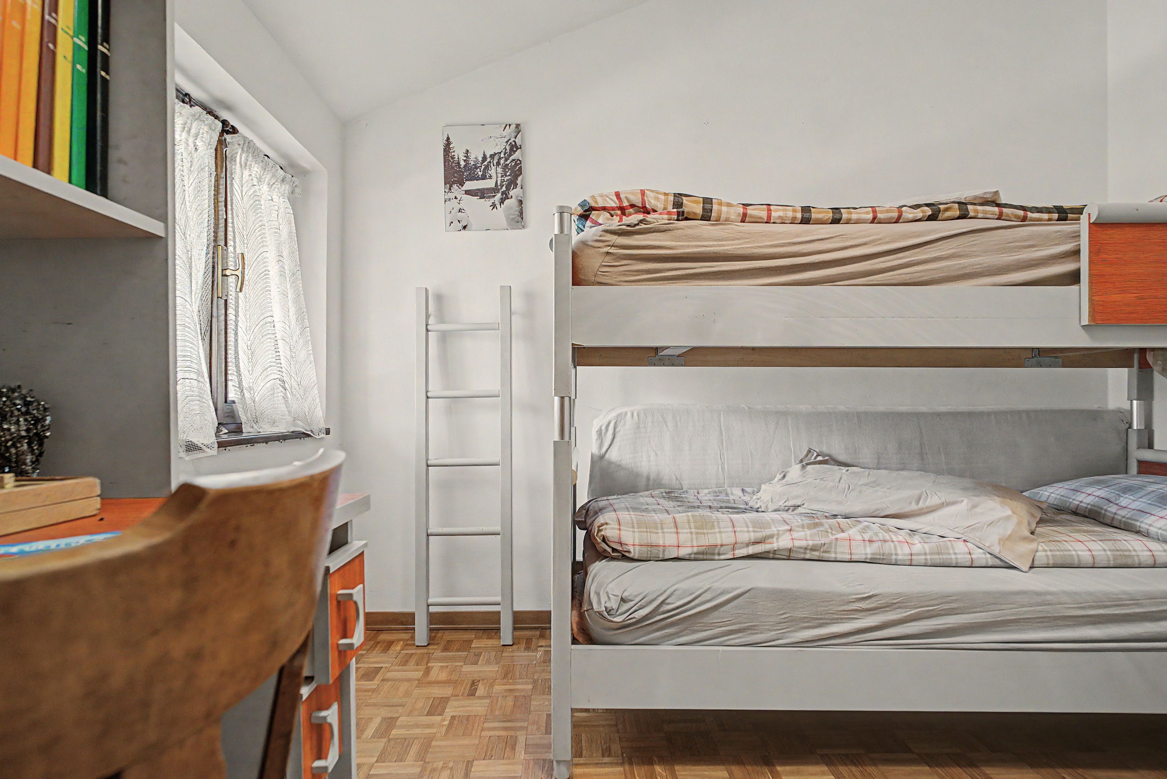 Un dormitorio con literas, un escritorio y una ventana con cortinas.