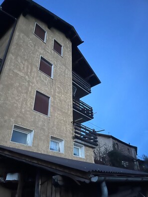 A multi-story building with a flat facade, multiple windows, and a balcony on the upper floor. - 'Il Rifugio del Brunone' Apartment with Mountain View, Balcony and Wi-Fi (Valda)