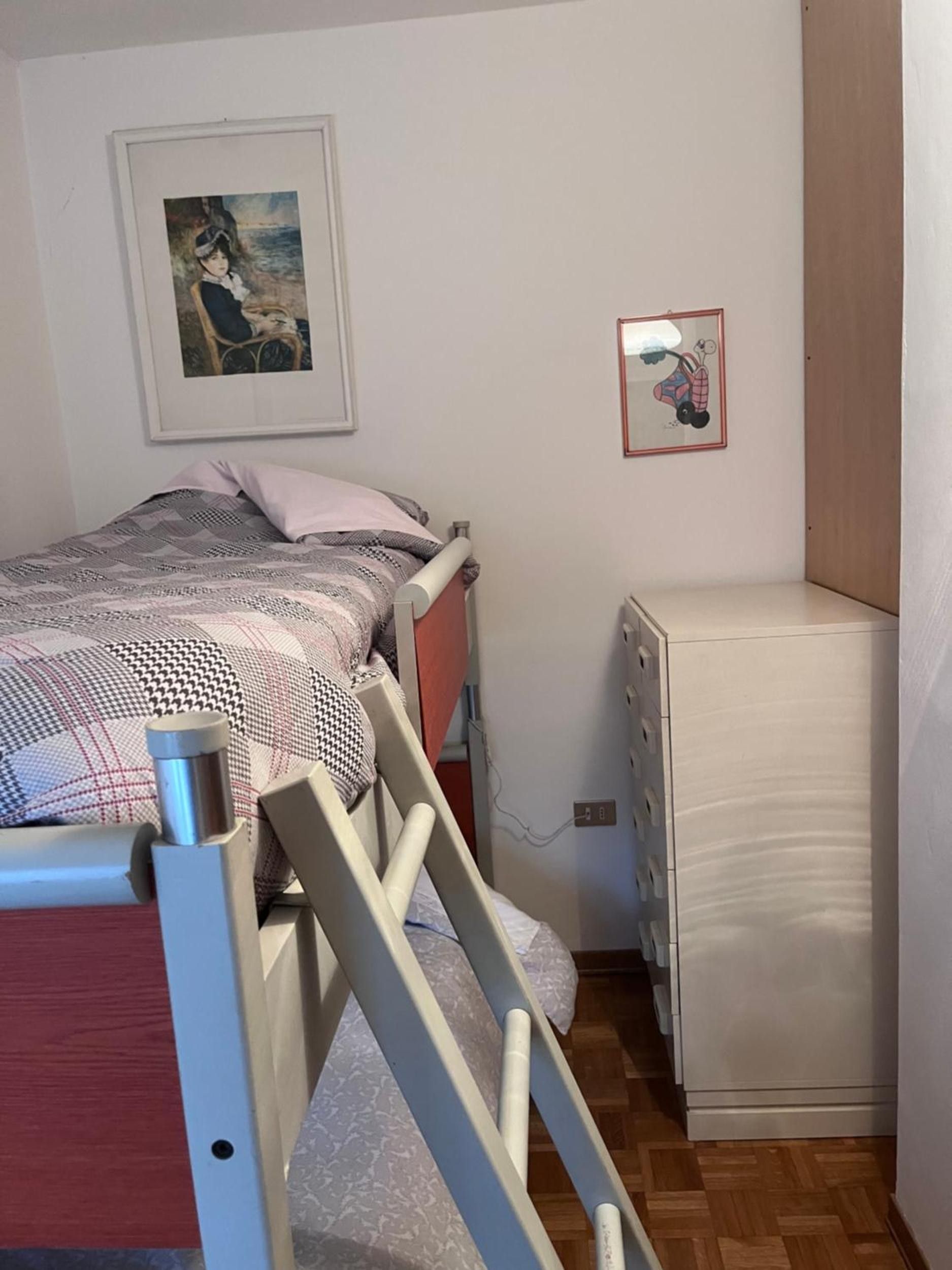 Una camera da letto con un letto, una cassettiera, un termosifone e un quadro appeso al muro.