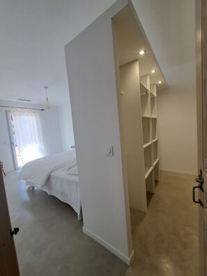 A bedroom with a bed, a closet with shelves, and a door leading to another room. - In Provence (Richerenches)