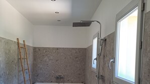 A bathroom with a bathtub, shower, and a window. - Vrbo Property (Richerenches)