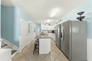 A kitchen with a stainless steel refrigerator, white cabinets, and a tiled floor. - Cherry Grove Villas 410-5BR-Beach Across Street (North Myrtle Beach)