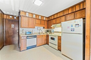 A kitchen with wooden cabinets, a dishwasher, a stove, and a refrigerator. - Sea Cabin 211- 2 Bedroom with Side Ocean View (North Myrtle Beach)