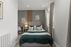 A bedroom with a bed, bedside table, lamp, and artwork on the wall. - Stylish 2-Bed House Near Leeds Centre | Parking (Leeds)