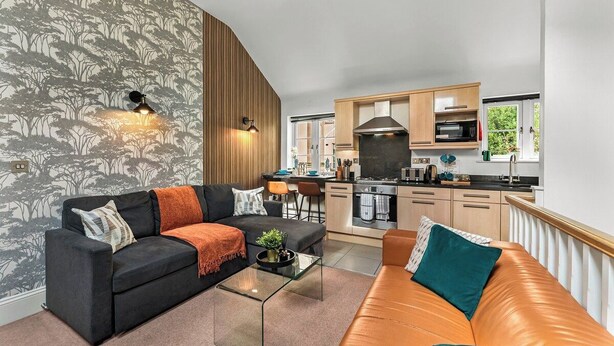 En moderne stue med sofa, sofabord og et køkken i baggrunden.