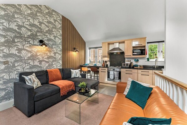 Ein modernes Wohnzimmer mit einer Couch, einem Couchtisch und einer Küche im Hintergrund.