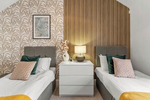 Ein Hotelzimmer mit zwei Betten, einem Nachttisch mit Lampe und einer dekorativen Wandverkleidung.