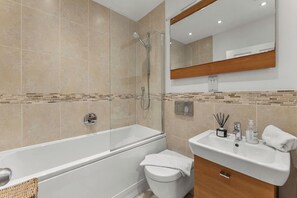 Ein modernes Badezimmer mit einer gläsernen Duschkabine, einer weißen Badewanne und einem Waschbecken mit Spiegel.