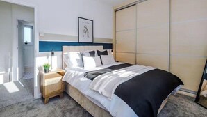 Een moderne slaapkamer met een bed, nachtkastje en een kledingkast.