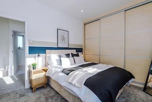 Ein modernes Schlafzimmer mit Bett, Nachttisch und Kleiderschrank.