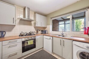 A compact kitchen with white cabinets, a microwave, a stove, and a dishwasher. - Elegant 4 Bed House - Parking and Garden -Sleeps 8 (Maidstone)