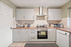 A compact kitchen with white cabinets, a stove, microwave, and dishwasher.