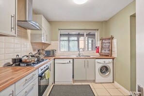 A compact kitchen with a stove, microwave, dishwasher, and a window.