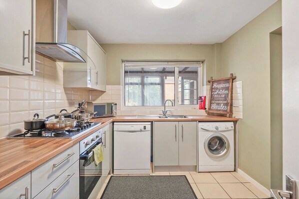A compact kitchen with a stove, microwave, dishwasher, and a window.
