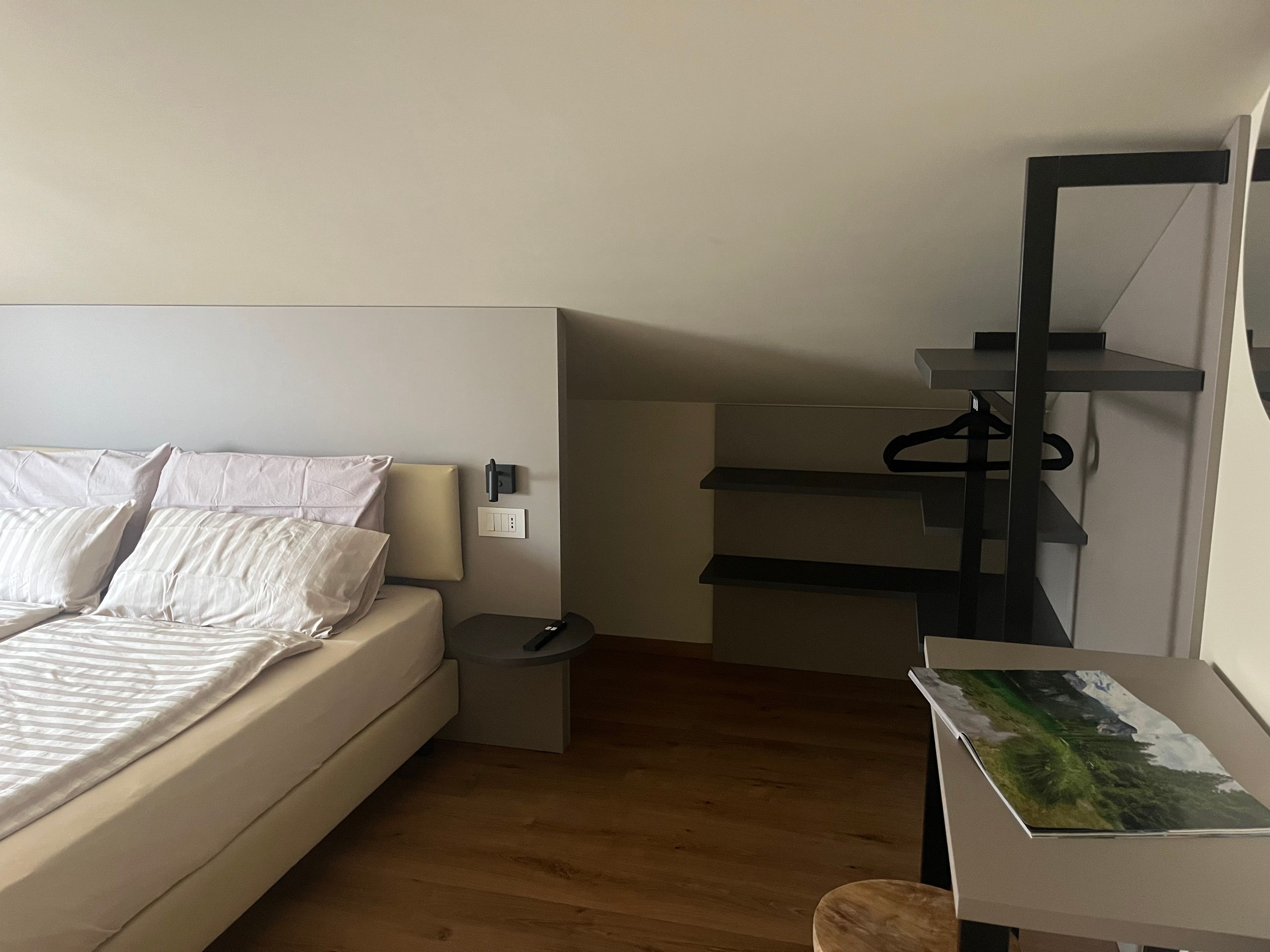 Een slaapkamer met een bed, nachtkastje en een bureau met stoel.