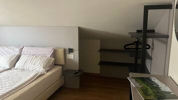 Een slaapkamer met een bed, nachtkastje en een bureau met stoel.