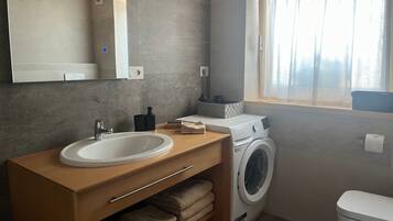 Un bagno moderno con lavandino, specchio, lavatrice e finestra con tende.