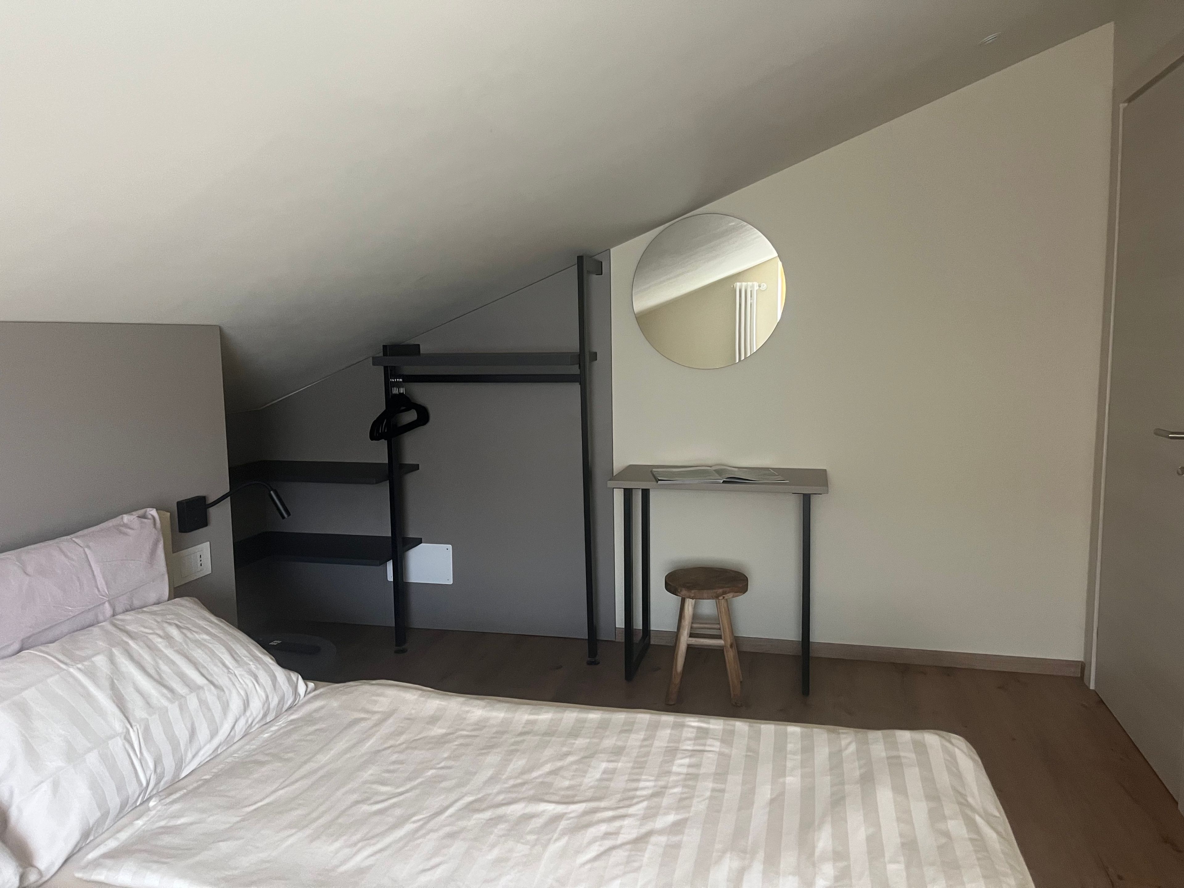 Une chambre à coucher avec un lit, un bureau, une chaise, un miroir et un lit superposé.