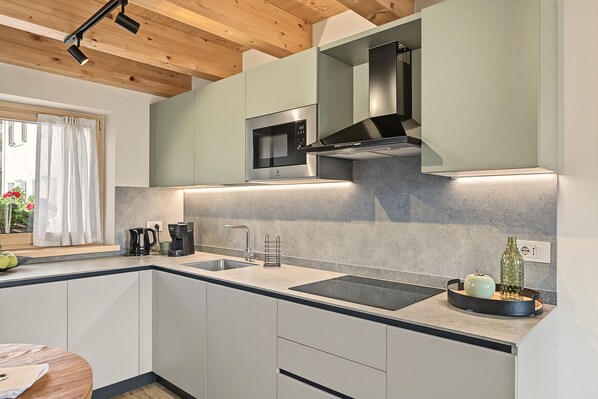 A modern kitchen with a built-in microwave, stainless steel range hood, and a double sink.