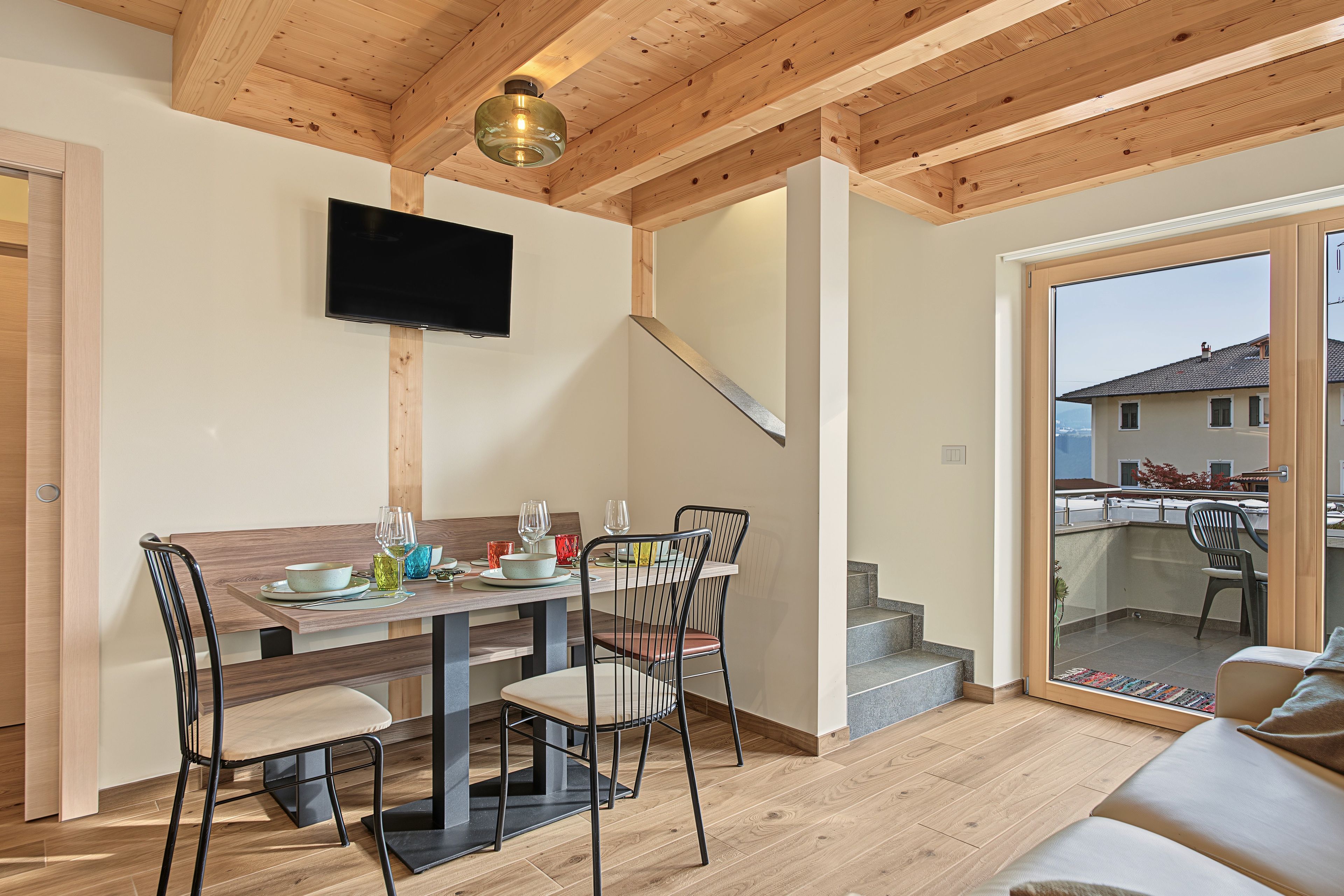 Ein moderner Essbereich mit Holztisch, Stühlen und einem an der Wand befestigten Flachbildfernseher.