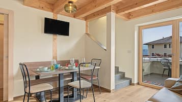 Ein moderner Essbereich mit Holztisch, Stühlen und einem an der Wand befestigten Flachbildfernseher.