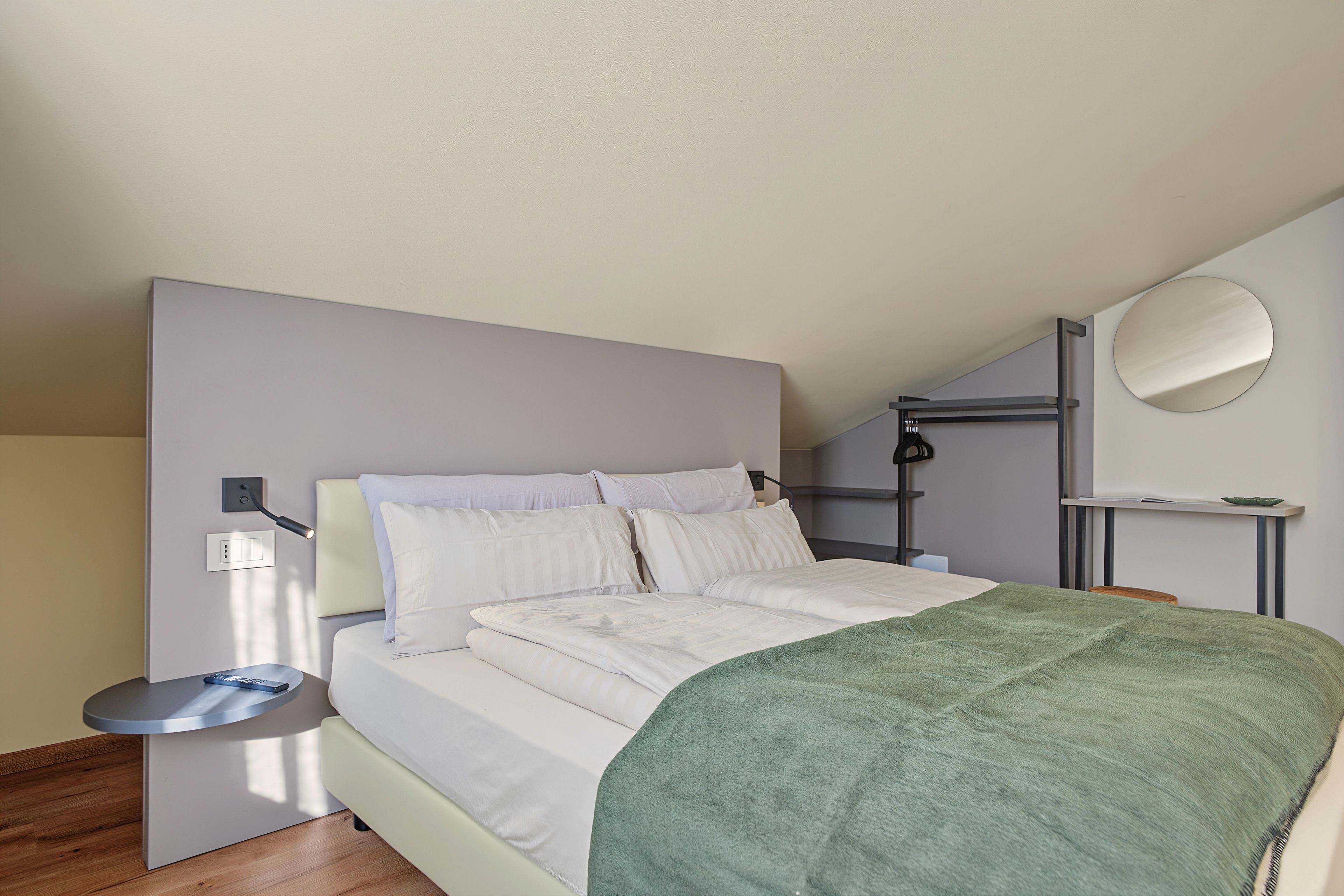 Una camera da letto moderna con un letto, un comodino e uno specchio fissato alla parete.