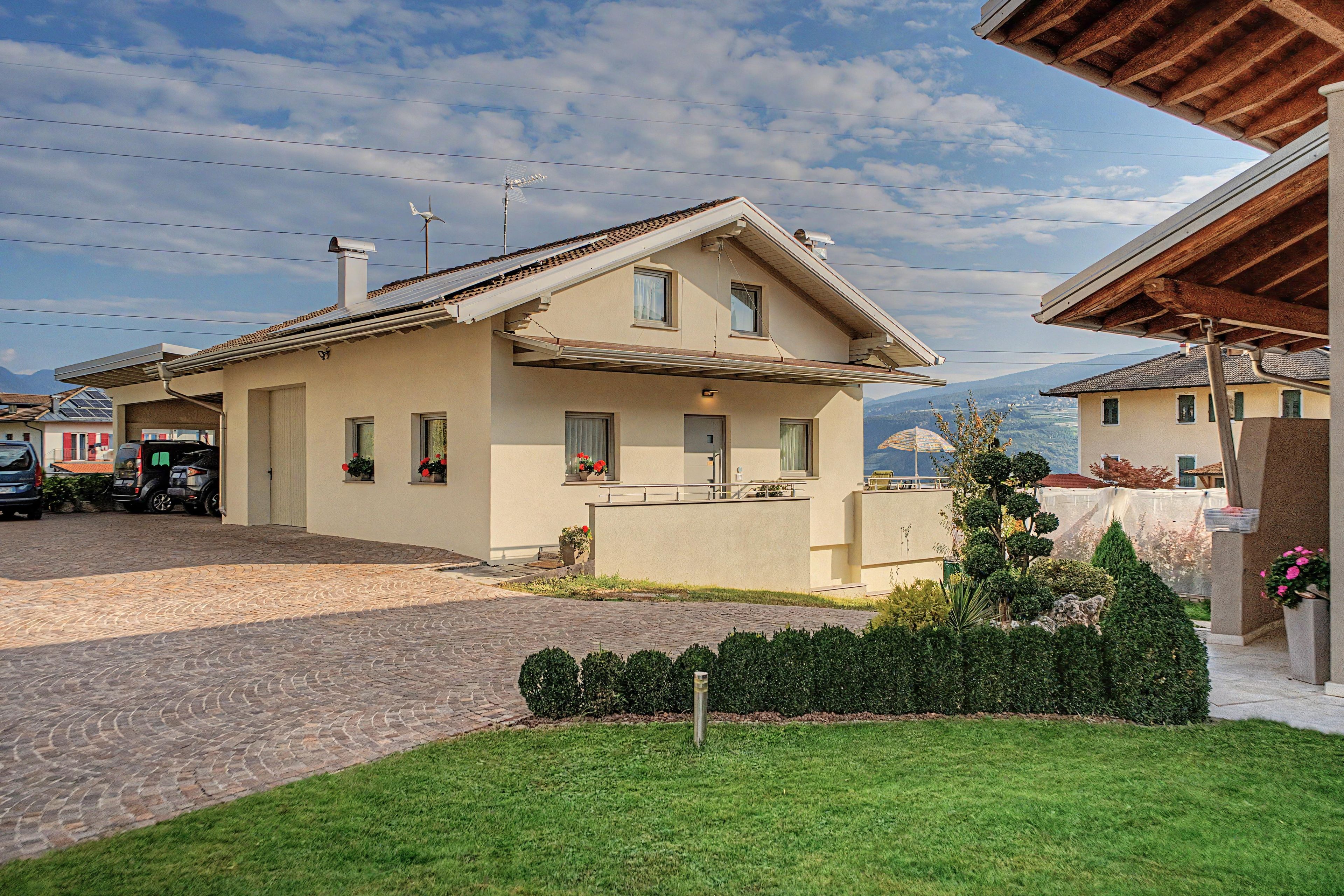 Une maison à deux étages avec un toit en pente, un garage et une allée pavée.