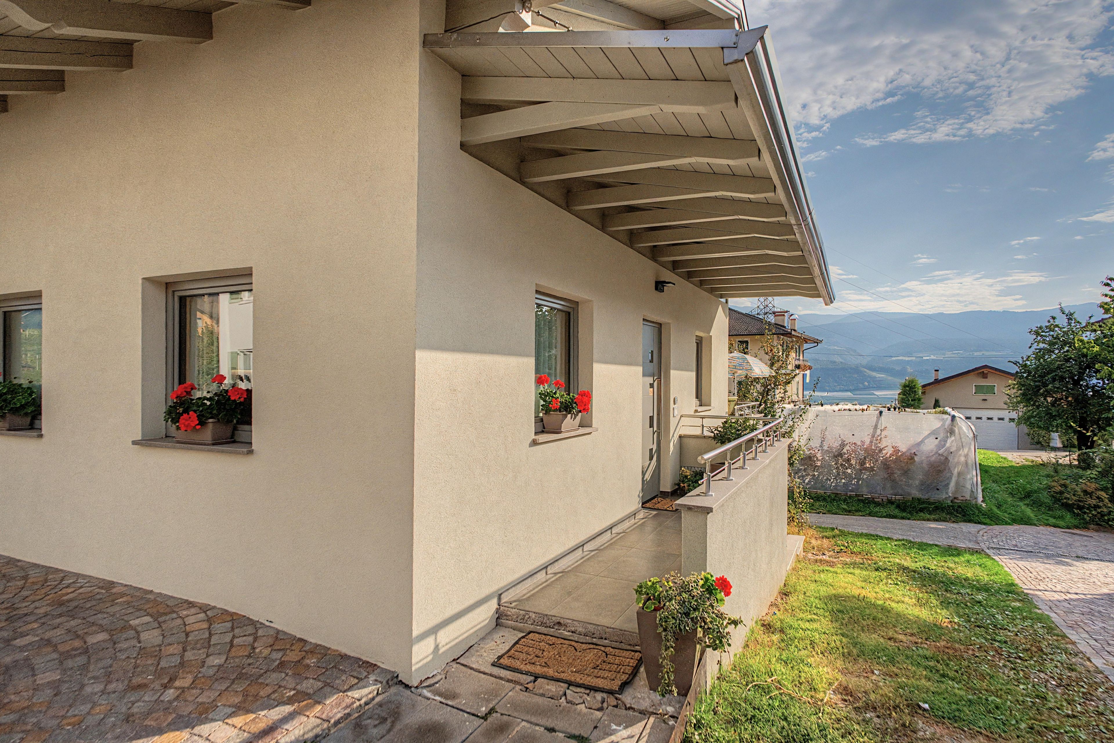 Ein zweistöckiges Gebäude mit Balkon, überdachter Veranda und Bergblick.