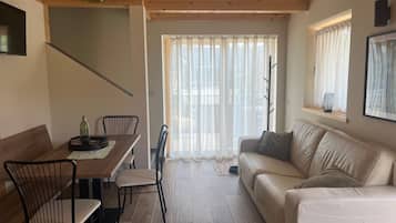 Un salon moderne avec une table à manger en bois, des chaises, un canapé et un escalier.