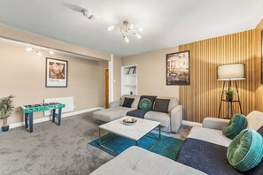 A living room with a sofa, coffee table, and a foosball table. - The Penthouse on Bristols Iconic Harbourside (Bristol)