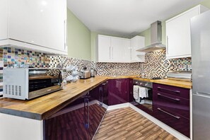 A modern kitchen with a wooden countertop, a built-in oven, and a tiled backsplash. - The Penthouse on Bristols Iconic Harbourside (Bristol)
