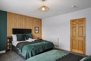 A bedroom with a bed, a bedside table, a wooden wall panel, a door, and a ceiling light fixture. - The Penthouse on Bristols Iconic Harbourside (Bristol)