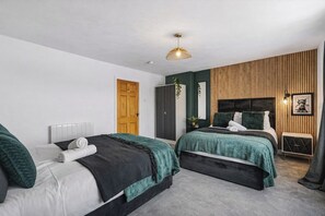 Ein modernes Schlafzimmer mit zwei Betten, einer Holz-Akzentwand und einer Pendelleuchte.