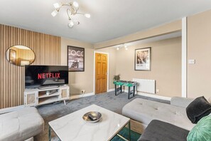 Ein modernes Wohnzimmer mit Fernseher, Sofa, Couchtisch und einem Kicker.